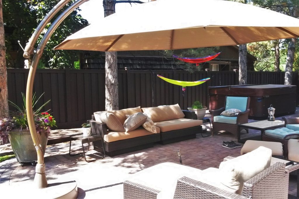 Backyard patio with furniture, shade structure, pavers, and a Trex fence